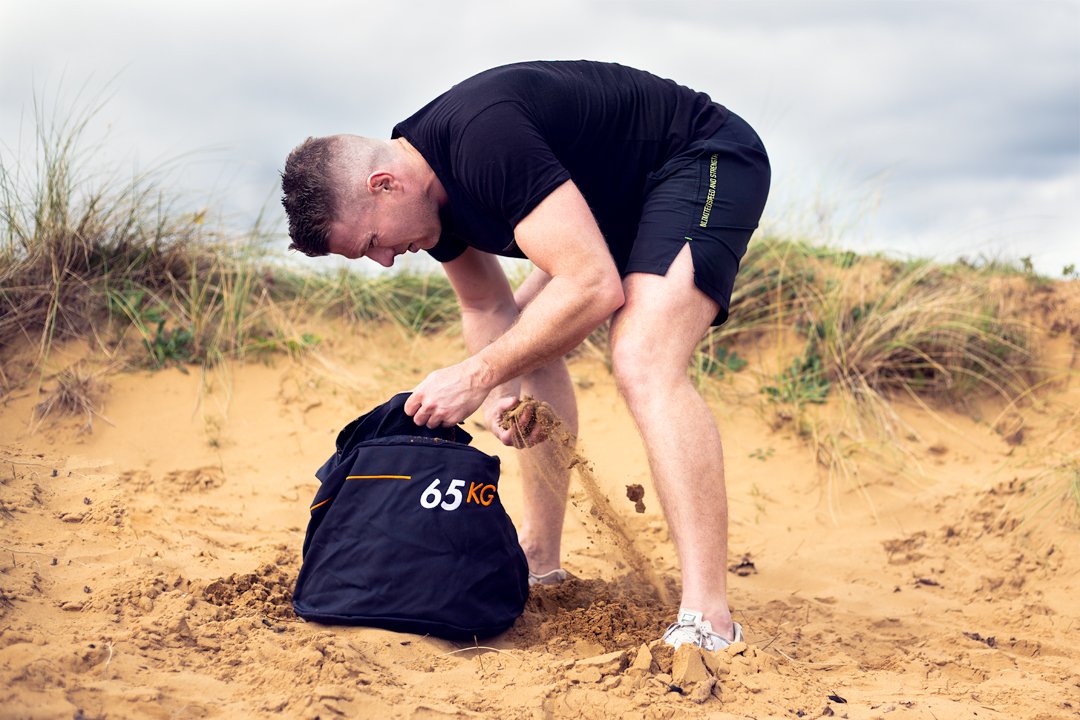 Athlete filling their Strongman Sandbag